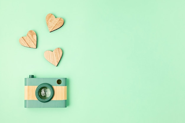 Lay Flat con cámara de madera de juguete y corazones. Redes sociales, publicaciones, me gusta, seguidores, concepto de clases de fotografía en línea. Vista superior, copie el espacio.