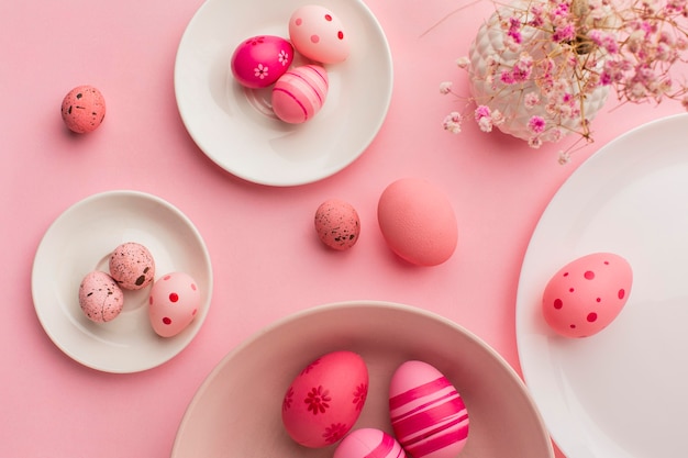 Foto lay flat de coloridos huevos de pascua en platos con papel y flores.