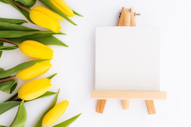 Lay Flat con flores de tulipán amarillo, marco de imagen vacío sobre fondo blanco. Concepto de tarjeta de felicitación para Pascua, día de la madre, día internacional de la mujer, día de San Valentín