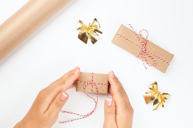 Lay Flat en las manos atando un hilo rojo en el paquete de regalo de Navidad aislado sobre fondo blanco con dec ...