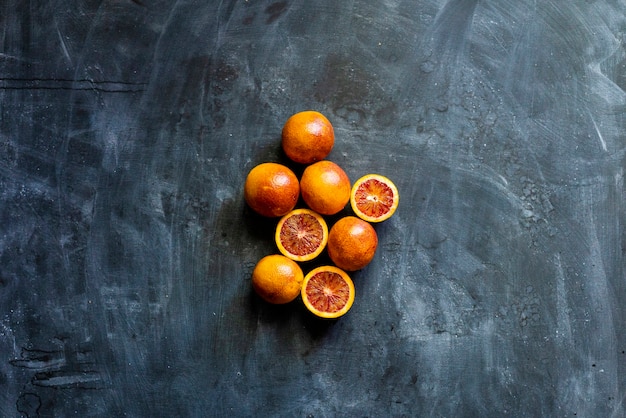 Lay Flat de naranjas exóticas en rodajas rojas, comida oscura sobre superficies negras