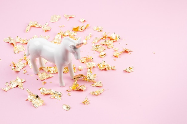 Lay Flat con unicornio blanco y brillo dorado sobre la pared rosa. Magia surrealista, estilo de cuento de hadas. Composición mínima