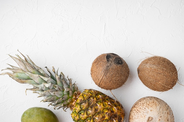 Layout criativo feito de frutas exóticas e tropicais, abacaxi e coco, no fundo da mesa de pedra branca, vista superior plana, com espaço de cópia para texto