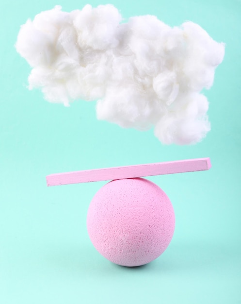 Layout criativo Feixe de equilíbrio em uma bola com uma nuvem em um fundo azul pastel minimalismo abstrato