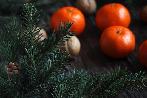 Layout de ano novo de ramos de abeto de tangerinas e nozes em um fundo de madeira