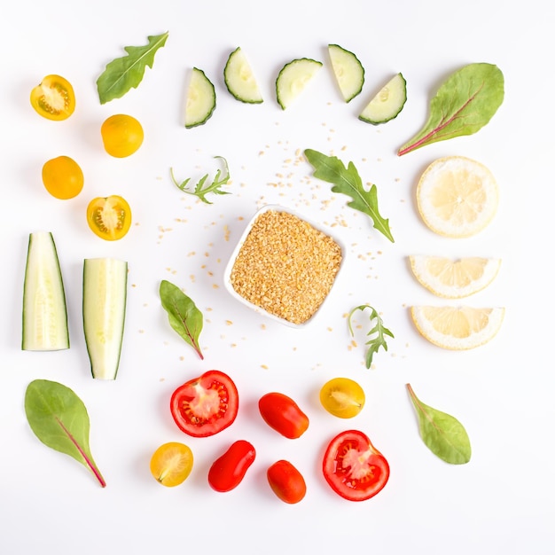 Layout de ingredientes de salada de tabule no conceito de knolling criativo de mesa branca Fundo de comida geométrica mínima com cereja tomotoes bulgur e verdes