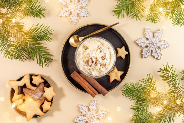 Layout de Natal com gemada cremosa, estrelas de cookies, galhos de pinheiro, flocos de neve, luzes de Natal em bege.