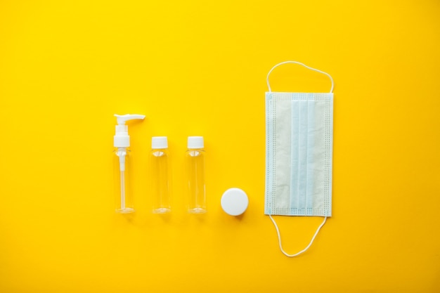 Foto layout em um fundo amarelo brilhante conjunto de frascos de cosméticos e máscara médica protetora