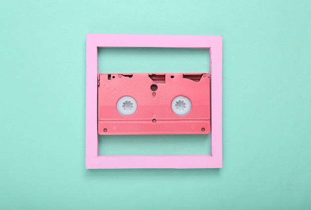 Layout retrô criativo dos anos 80 cassete de vídeo rosa com moldura em fundo azul menta minimalismo flat lay vista superior