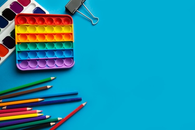 Foto layout vista superior de itens escolares infantis pop it toy aquarelas a lápis de cor