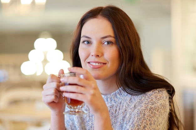 lazer, bebidas, pessoas e conceito de estilo de vida - jovem sorridente bebendo chá no café