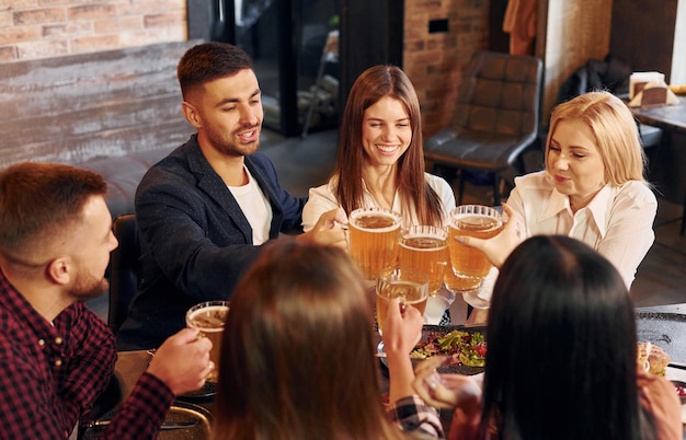 Lazer de fim de semana Grupo de jovens amigos sentados juntos no bar com cerveja