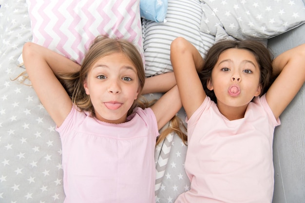 Lazer e diversão. Se divertindo com o melhor amigo. Humor alegre lúdico de crianças se divertindo juntos. Festa do pijama e amizade. Irmãs felizes crianças pequenas relaxantes no quarto. Amizade de meninas pequenas.