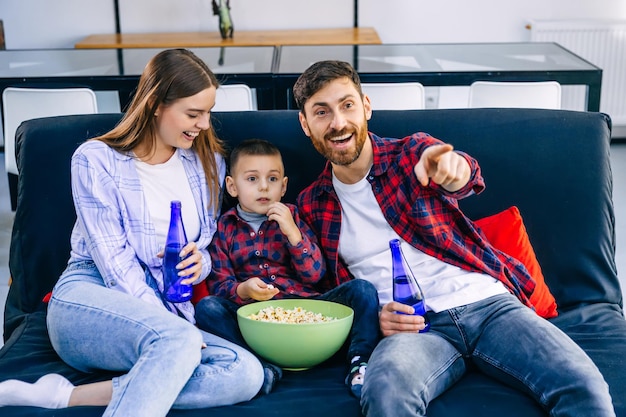 Lazer familiar e conceito de pessoas feliz sorridente pai mãe e filho pequeno comendo pipoca e assistindo tv