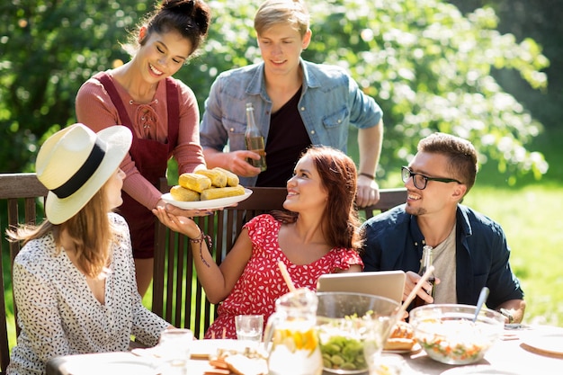 lazer, férias, alimentação, pessoas e conceito de comida - amigos felizes jantando na festa do jardim de verão