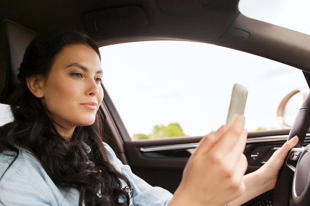 lazer, viagem, tecnologia, viagens e conceito de pessoas - mulher feliz dirigindo carro com smarhphone