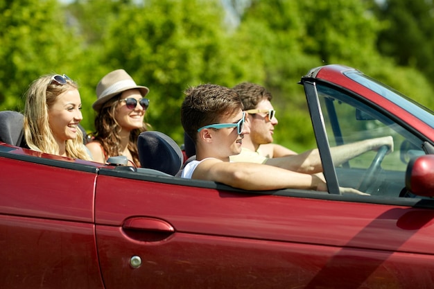 lazer, viagem, viagens e conceito de pessoas - amigos felizes dirigindo em carro cabriolet ao longo da estrada rural