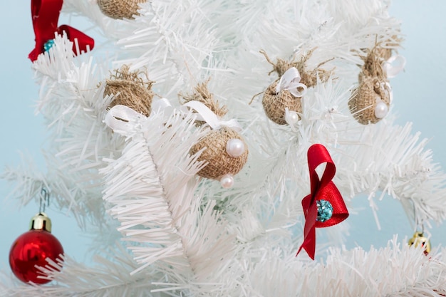 Lazo rojo en un primer plano de árbol de navidad blanco