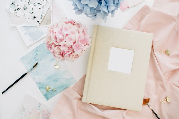 Álbum de fotos de casamento de família, buquê de flores de hortênsia colorida em tons pastéis, cobertor cor de pêssego, decoração na superfície branca