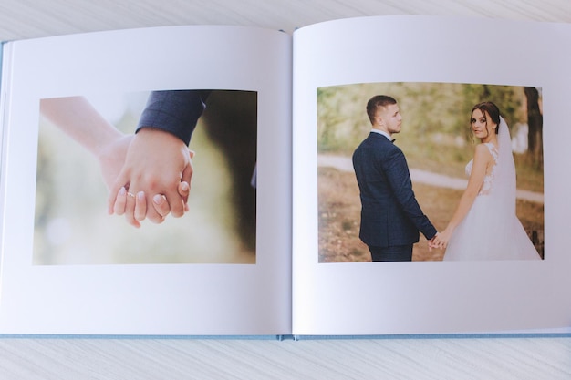 Álbum de fotos abierto con una foto de una hermosa pareja en una mesa de madera blanca