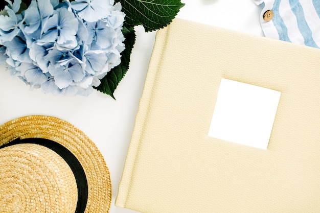 Álbum de fotos de boda familiar, ramo de flores de hortensias azules, manta de rayas, sombrero de paja, decoración en superficie blanca