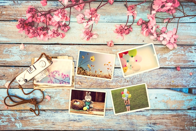 Álbum de fotos de cámara y papel retro en mesa de madera con diseño de borde de flores