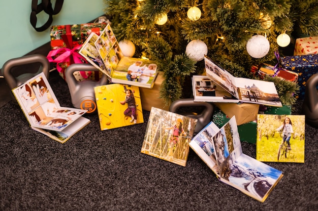 Álbum de fotos familiar y pesas para deportes cerca del árbol de Navidad.