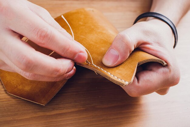 leather craftsman working making products at table in workshop studio