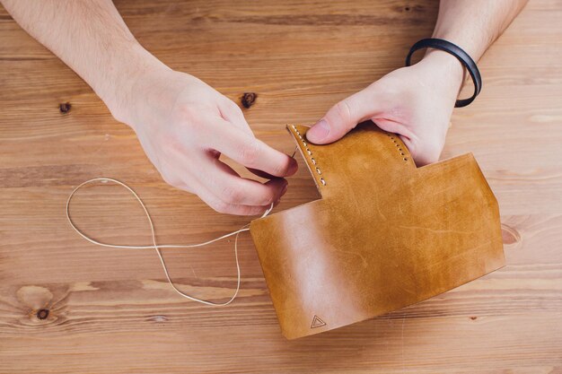 leather craftsman working making products at table in workshop studio