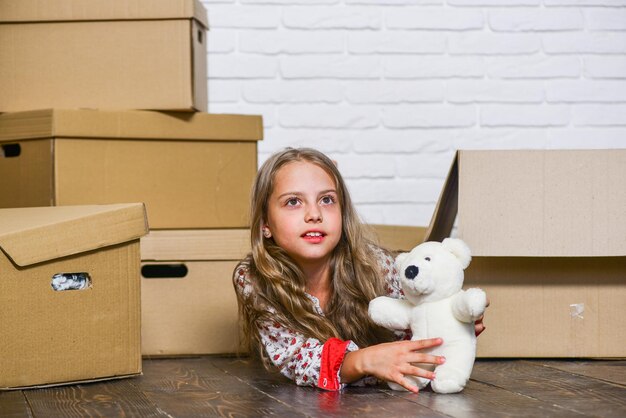 Leaving Home glückliches kleines Mädchen mit Spielzeug Kauf einer neuen Wohnung glückliches Kind Karton Umzugskonzept neue Wohnung Kartons Umzug in neues Haus