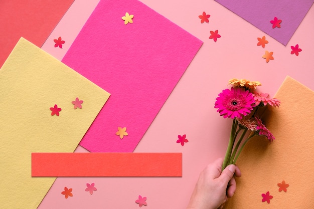 Lebendige flache Lage mit Gerbera-Gänseblümchenblüten auf korallenfarbenem Papier. Kreatives flaches, getöntes Bild.