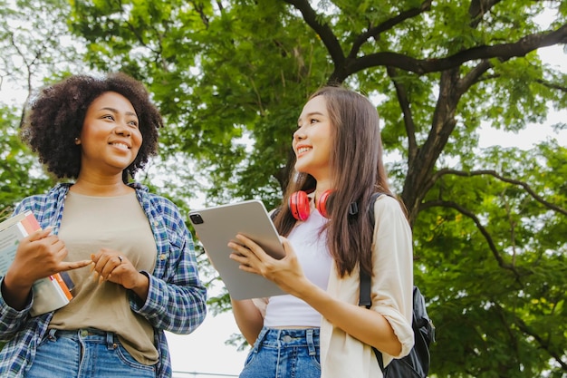 Lebendiges Bild Zwei asiatische und afroamerikanische Studentinnen gehen durch die Schönheit der glücklichen Stadtanlage