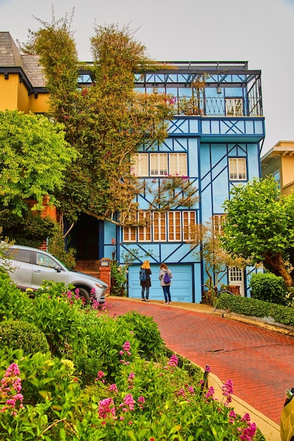 Lebendiges blaues Haus an der Westküste an der Straße aus rotem Backstein und Frühlingsblumen