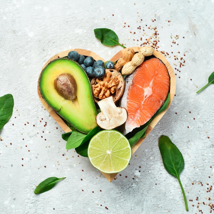 Foto lebensmittel, die gut für das herz sind nüsse lachs avocados spinat pilze beeren in einer herzförmigen box auf einem steinhintergrund ansicht von oben kopieren sie platz