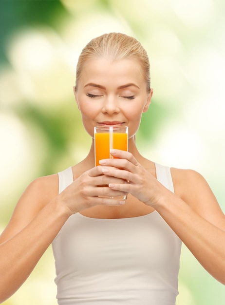 Lebensmittel-, Gesundheits- und Diätkonzept - junge Frau, die Orangensaft trinkt