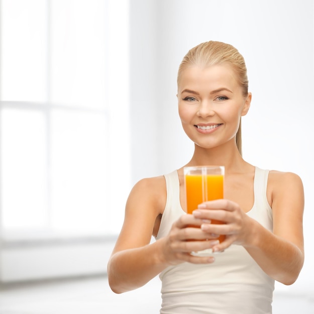 Lebensmittel-, Gesundheits- und Diätkonzept - lächelnde junge Frau, die ein Glas Orangensaft hält