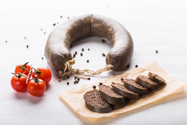 Lebensmittel-, Küchen- und Pferdefleischkonzept - Nahaufnahme von Fleischwurst mit Tomaten und Pfeffer auf Kraft