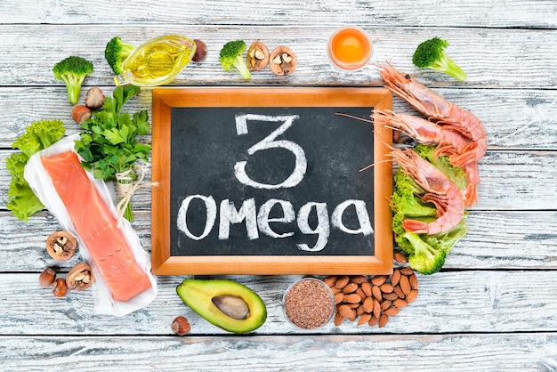 Lebensmittel mit Omega-3-Vitamin Gesunde Lebensmittel Avocados Fisch Garnelen Brokkoli Leinsamen Eier Petersilie Ansicht von oben Freier Platz für Ihren Text Auf einem weißen Hintergrund aus Holz