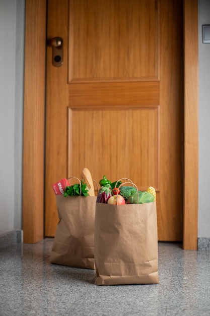 Lebensmitteleinkaufstüten stehen an der Tür des Hauses oder der Wohnung. Lieferung von Gemüse und Obst während der Quarantäne und Selbstisolation.