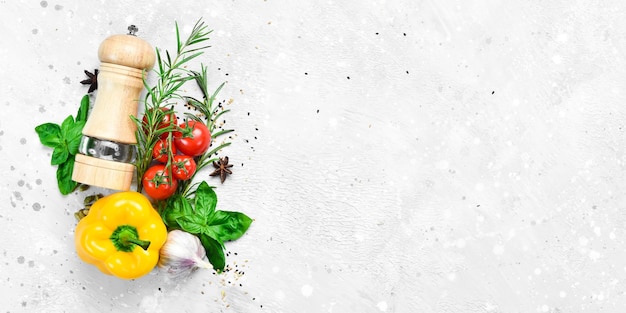 Lebensmittelhintergrund Gemüse, Gewürze und Pfeffermühle auf grauem Steinhintergrund Draufsicht Freier Platz für Text