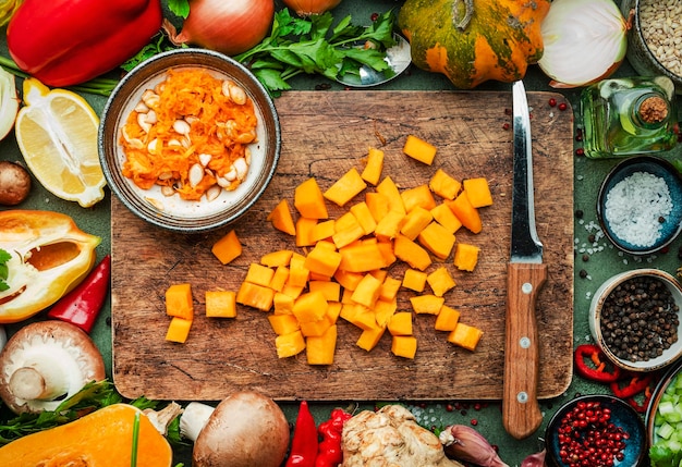 Lebensmittelhintergrund Geschnittener Kürbis und Messer auf Schneidebrett Gemüse Pilze Wurzeln Gewürze Zutaten für veganes Kochen Gesunde Ernährung Komfort Slow Food Konzept Rustikale Tischansicht
