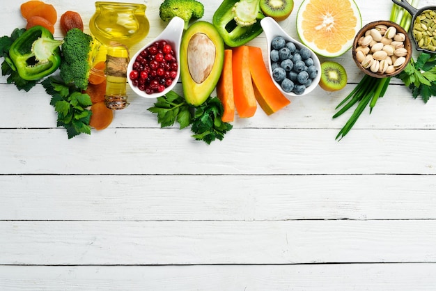 Lebensmittelhintergrund: Obst, Gemüse und Beeren auf weißem Holzhintergrund. Ansicht von oben. Rustikaler Stil.