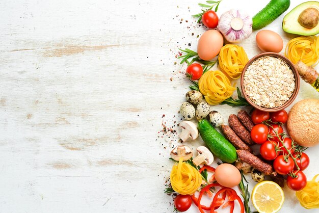 Lebensmittelhintergrund Trockene Nudeln, Tomaten, Gewürze und Gemüse auf einem weißen Holzhintergrund Draufsicht