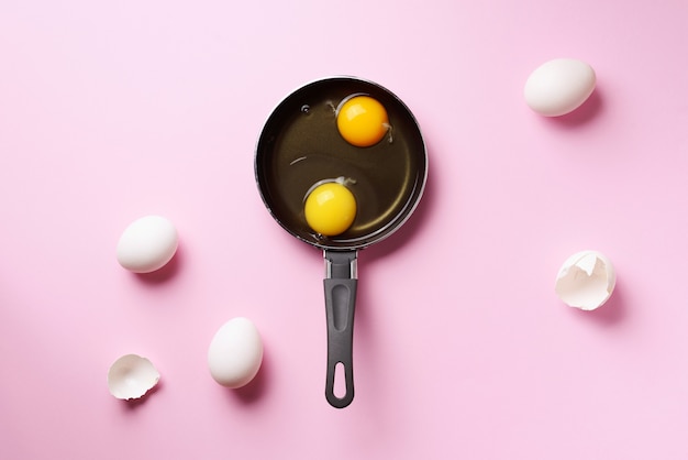 Lebensmittelkonzept mit zwei Eiern, Oberteile, Wanne auf rosa Hintergrund
