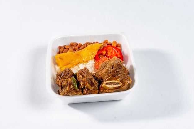 Lebensmittellieferung, Lunchpaket mit Rinderrippen gekocht mit Maniok, Reis, Bohnen und Tomaten isoliert auf weißem Hintergrund.