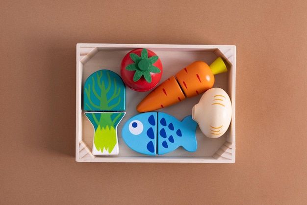 Lebensmittelspielzeug auf braunem Hintergrund kreatives Holzdesign Vegetarisches Gemüse- und Fischkind entwickeln sich
