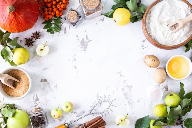 Lebensmittelzutaten für die Herstellung von Herbstkürbiskuchen auf weißem Steinhintergrund. Hausgemachtes Backkonzept. Rahmen