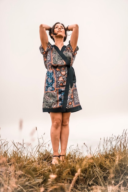 Lebensstil, brünettes Mädchen, das Natur mit buntem Kleid auf einem Berg genießt