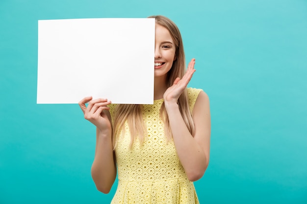 Lebensstil-Konzept: junges schönes Mädchen, das lächelt und ein leeres Blatt Papier hält