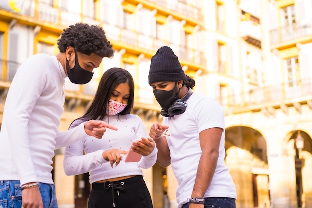 Lebensstil, Latino-Freunde, die Spaß mit Gesichtsmasken haben, die etwas am Telefon betrachten.